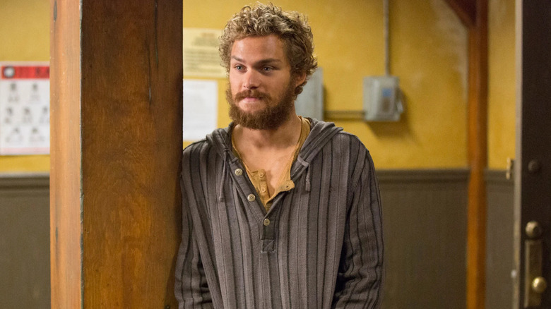 Danny Rand leans on a pole in a dojo.