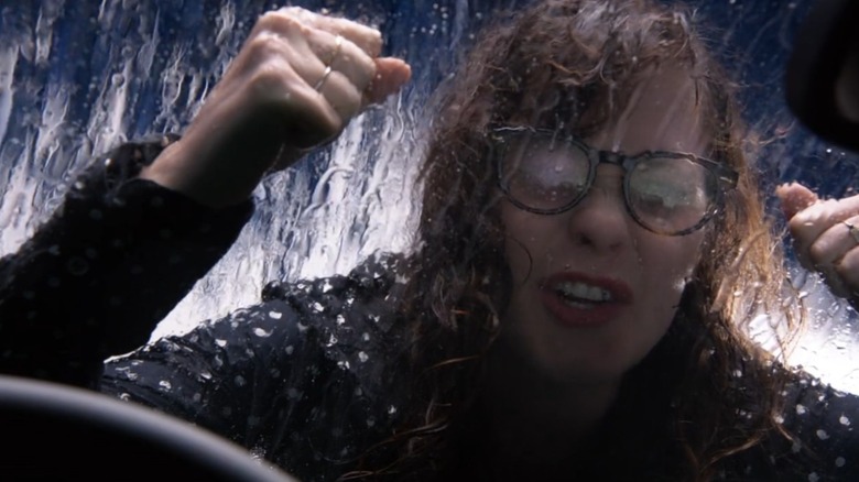 Jess jumps on the hood of a car in a car wash
