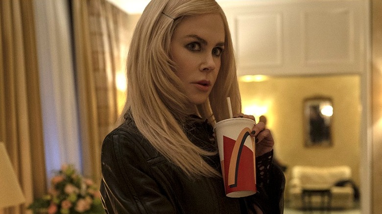 Masha holding a McDonald's cup and looking over her shoulder in Nine Perfect Strangers