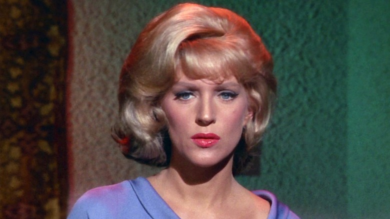 Nurse Chapel in a blue uniform standing in front of a green wall in Star Trek