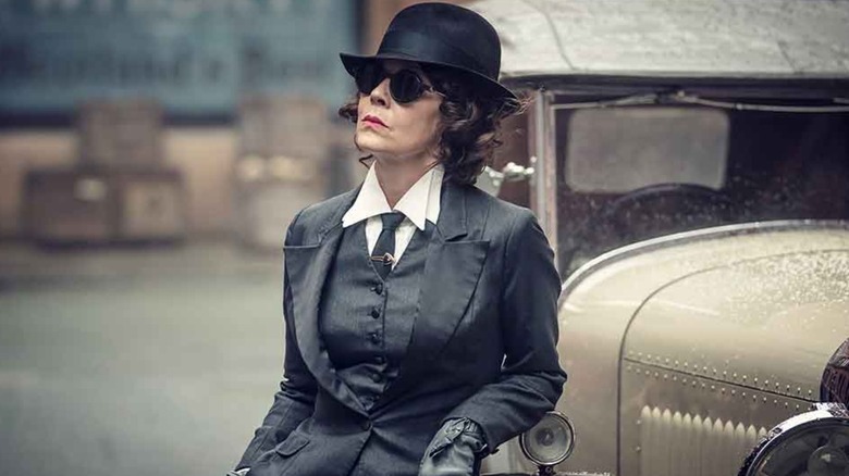 Polly in sunglasses leaning against a car in Peaky Blinders
