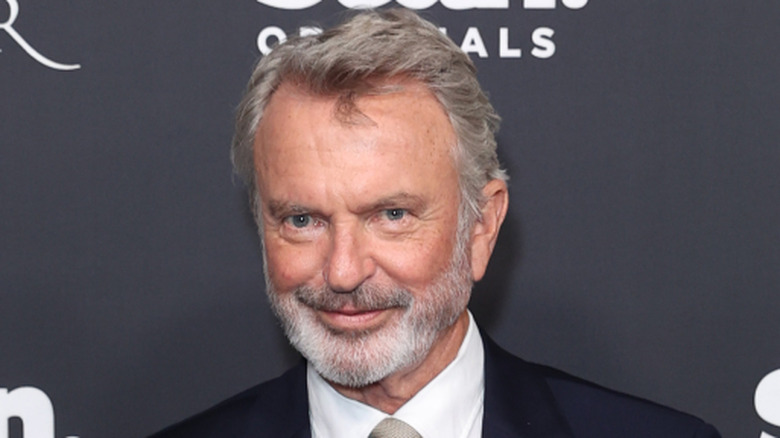Sam Neill smiling at a red carpet event