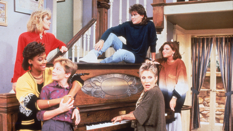 the cast of The Facts of Life (1979) gathered around a piano on the show's set