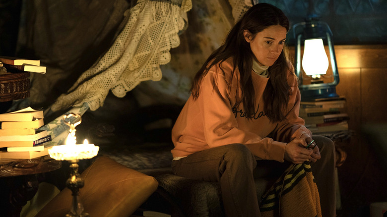 Shailene Woodley sits near a lantern and looks despondent in Paradise