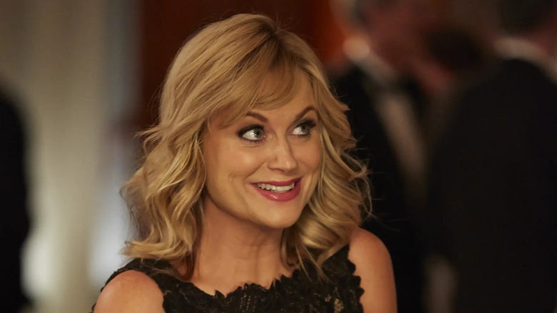 Amy Poehler as Leslie Knope smiling in a black dress in Parks and Recreation