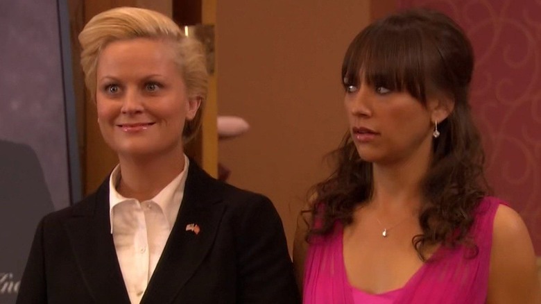 Amy Poehler as Leslie Knope dressed in a suit with Rashida Jones as Ann Perkins staring at her in a pink dress in Parks and Recreation