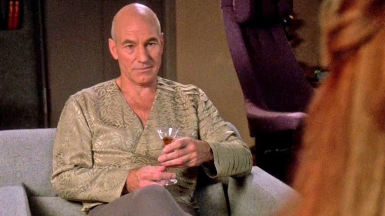 Picard holding a drink in a fancy shirt in Star Trek