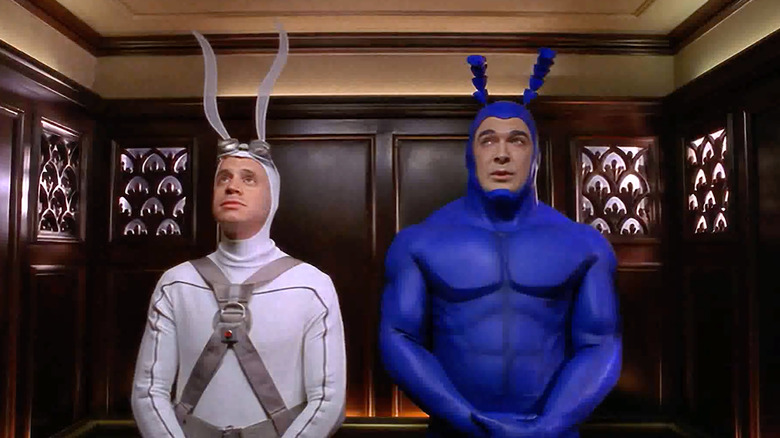 Arthur (David Burke) in a white moth costume; The Tick (Patrick Warburton) in blue. Both in an elevator.