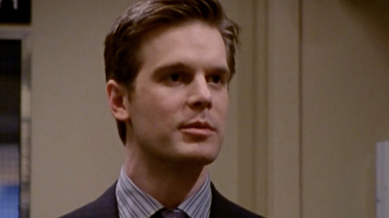 Casey McCall in dark suit standing in Sports Night studio