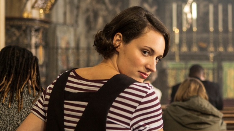 Fleabag looking over her right shoulder with a smirk while sitting in a church pew