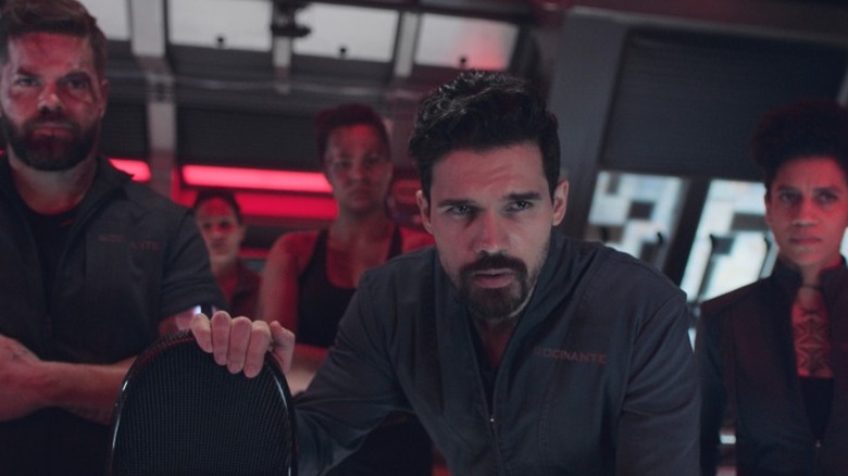 Jim Holden standing in the center of his crew on a spaceship