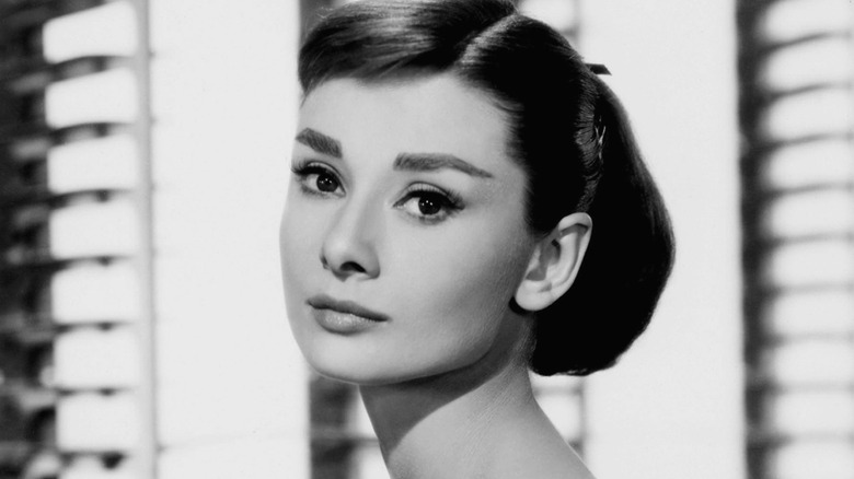 Audrey Hepburn poses as Jo Stockton in "Funny Face," wearing a ballgown and her hair in a low bun.