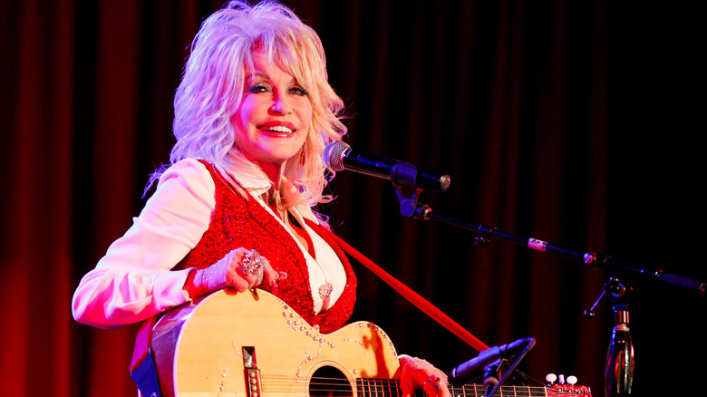 Dolly Parton singing and playing the guitar at Stella Parton's Red Tent Women's Conference 2014 at the Doubletree Hotel Downtown on April 18, 2014 in Nashville, Tennessee.