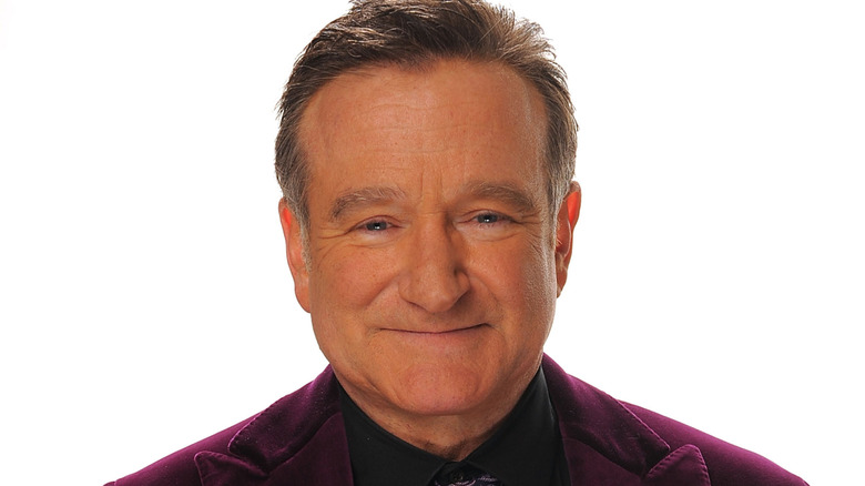 Actor Robin Williams poses for a picture while wearing a purple suit