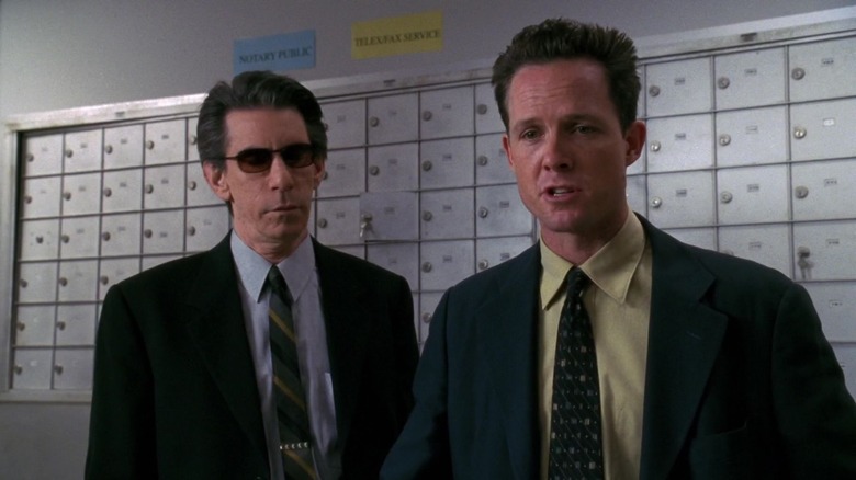 Detectives Munch (Richard Belzer) and Cassidy (Dean Winters) wear suits and ties while standing in front of a wall of mailboxes in "Law and Order: SVU"