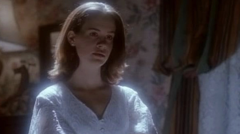 Sarah Paulson as Marilyn standing in a white blouse with a glowing light on her in American Gothic