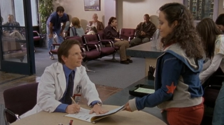 Kevin Casey (Michael J. Fox) signing a paper and talking to Carla (Judy Reyes) in Scrubs