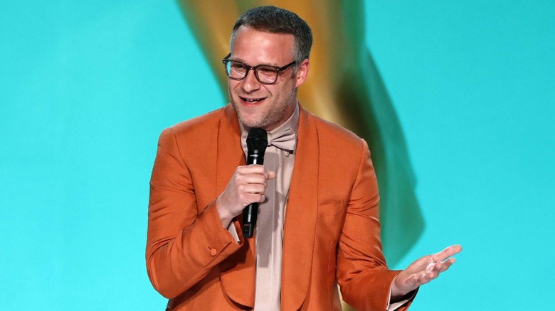 Seth Rogen holds a mic while wearing an orange suit while presenting at the 2021 Emmy Awards