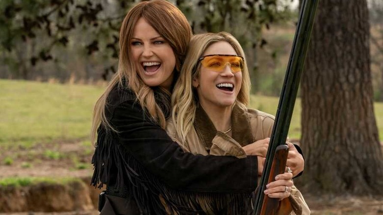 Malin Akerman and Brittany Snow as Margo and Sophie in an embrace while Sophie holds a shotgun in The Hunting Wives
