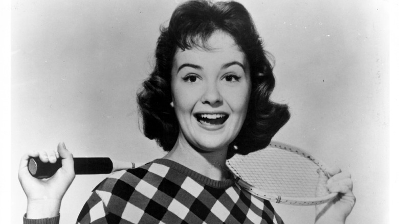 Shelley Fabares, holding a tennis racket behind her and smiling