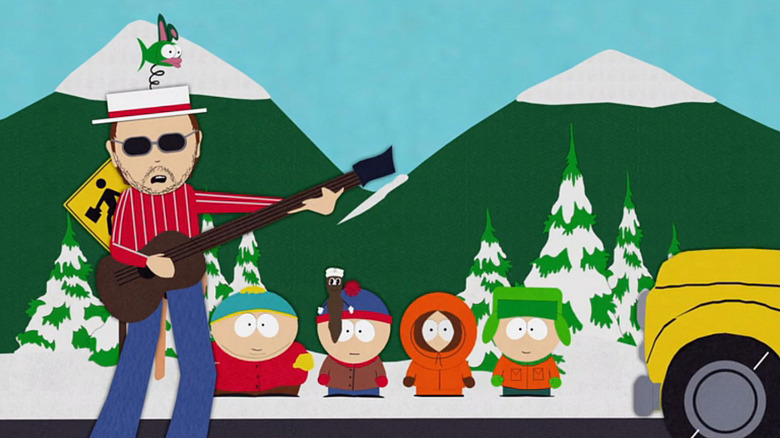 Les Claypool playing guitar on the road while Eric Cartman, Mr. Hankey, Stan Marsh, Kenny McCormick, Kyle Broflowski watch on South Park