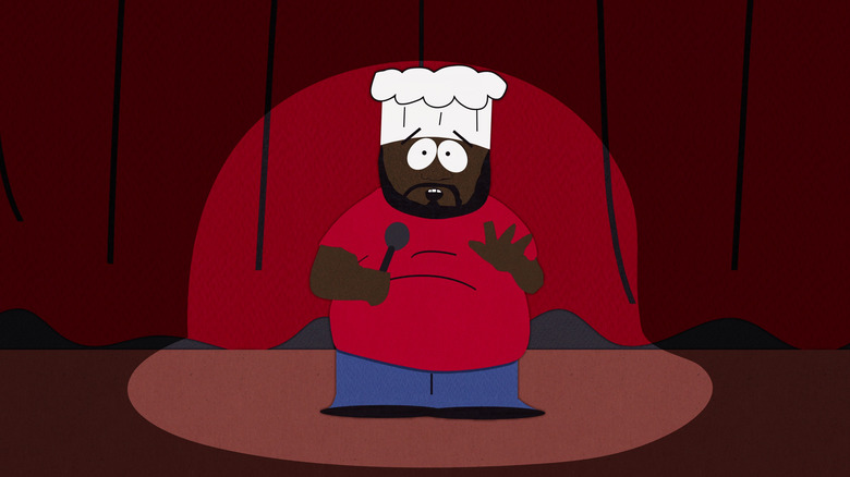 Chef (Isaac Hayes) se apresenta com microfone no palco 