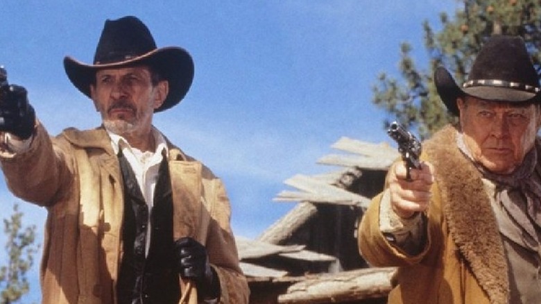 Frank James and Bronc Evans pointing revolvers.