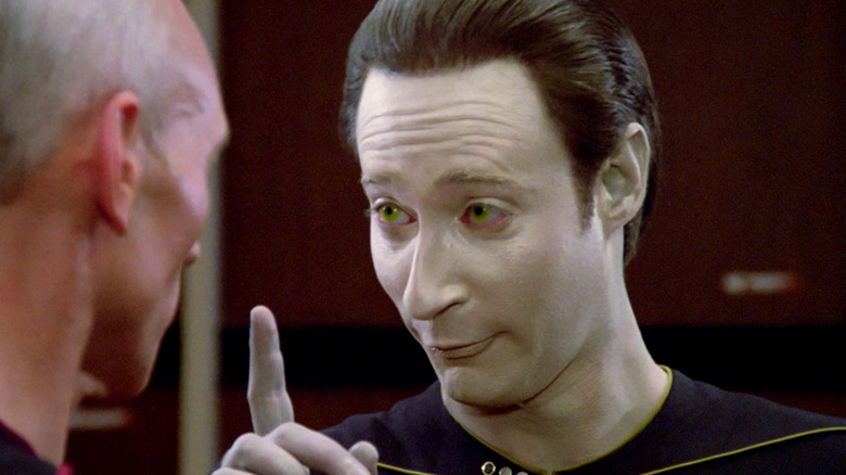 Data (Brent Spiner) raises a finger with a goofy look on his face while speaking to Jean-Luc Picard (Patrick Stewart) in Star Trek: The Next Generation