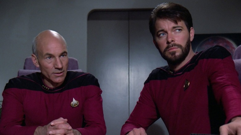 Captain Jean-Luc Picard talking to someone on the Enterprise while Commander William T. Riker looks to the side