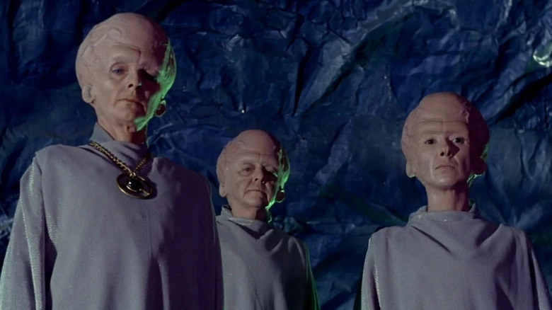Three aliens from the Talosian race looking down at someone in a cave