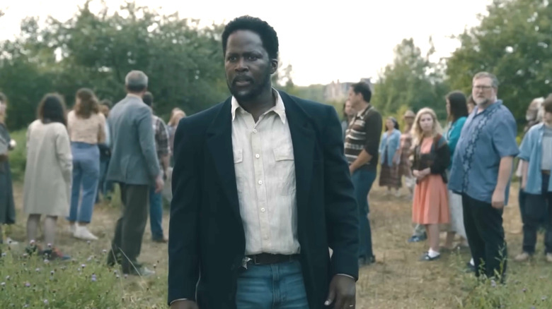 Boyd Stevens standing in front of the townspeople outdoors in From.