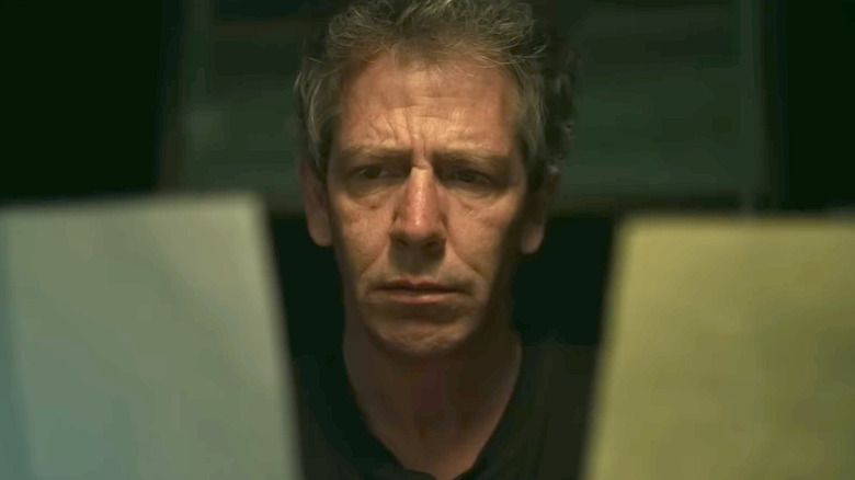 Detective Ralph Anderson looking at two pieces of paper