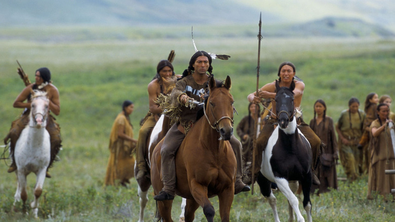 Native American warriors ride horses across an open plain in Into the West (2005)