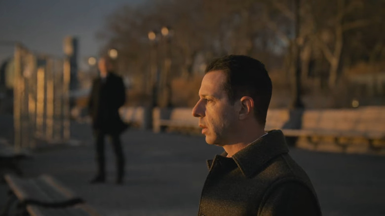 Jeremy Strong as Kendall Roy, looking out into the Hudson River as Colin watches from a distance on Succession