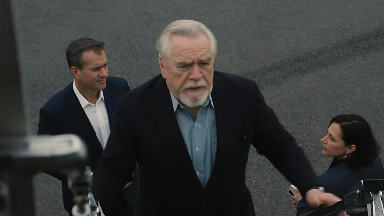 Brian Cox as Logan Roy, walking past Tom and Karolina into a plane on Succession