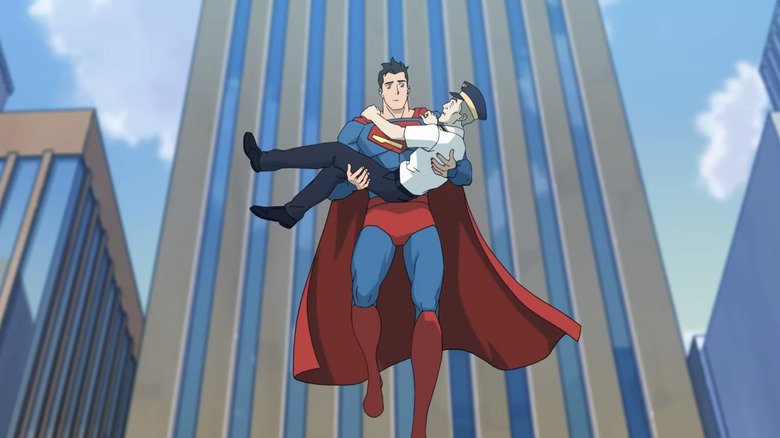 Superman in his classic costume floating in a city carrying a civilian in his arms in "My Adventures with Superman."