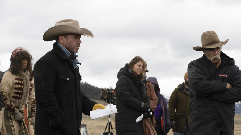 Taylor Sheridan holding a piece of paper on the set of 1883 alongside Sam Elliott