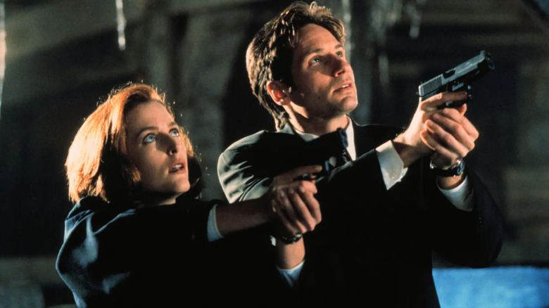FBI agents Scully and Mulder draw their guns on a threat in The X-Files.