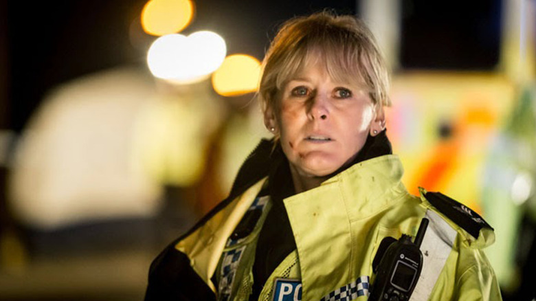 A scuffed-up Catherine Cawood (Sarah Lancashire) stands in her police uniform on Happy Valley