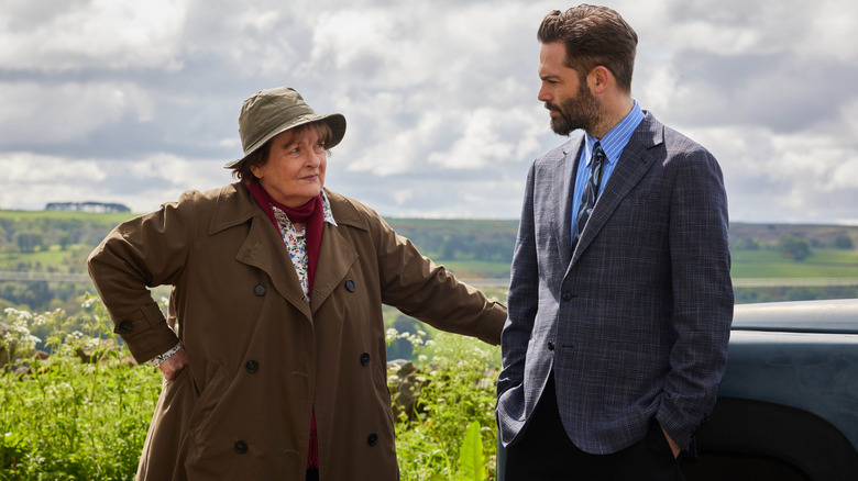 Vera Stanhope (Brenda Blethyn) glances at Joe Ashworth (David Leon) by a car overlooking the countryside on Vera