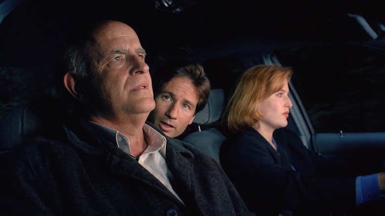 Peter Boyle as Clyde Bruckman in car with David Duchovny as Mulder in backseat and Gillian Anderson as Scully driving in The X-Files