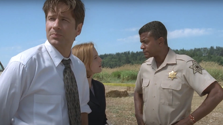 Mulder (David Duchovny) and Scully (Gillian Anderson) talk to Sheriff Taylor (Tucker Smallwood) on The X-Files