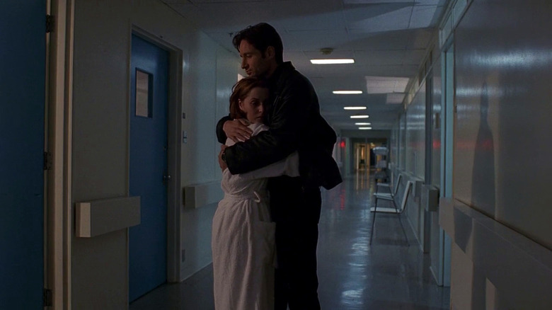 Gillian Anderson as Scully and David Duchovny as Mulder hugging in empty hospital hallway in The X-Files