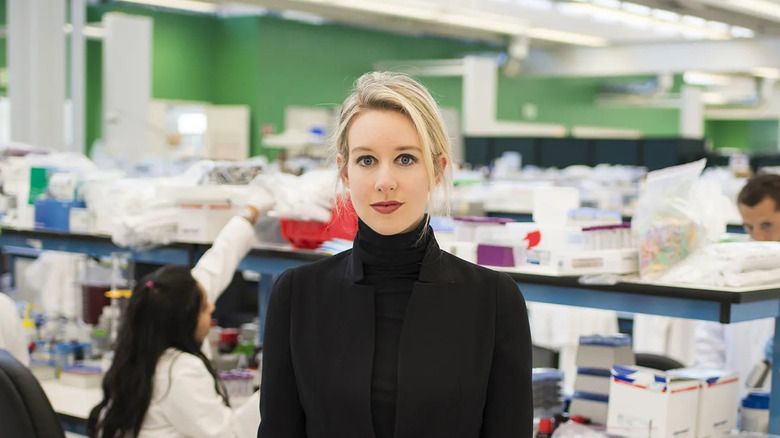 Elizabeth Holmes, clad in all black, stares directly into the camera in a pharmaceutical lab in The Inventor: Out for Blood in Silicon Valley