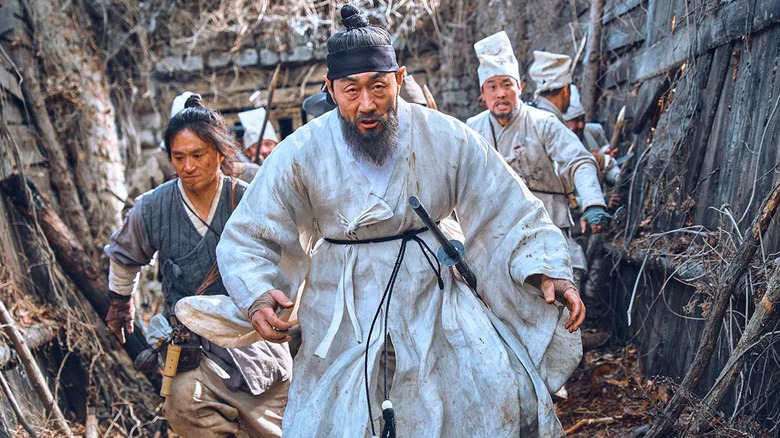 Ahn Hyeon (Huh Joon-ho) runs through wooden and stone barricades ahead of soldiers on Kingdom