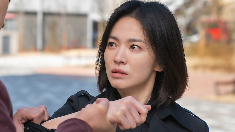 Moon Dong-eun (Song Hye-kyo) glares intensely at someone holding her wrist in The Glory