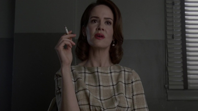 Sarah Paulson in checkered top holding a cigarette as Lana Winters on American Horror Story: Asylum