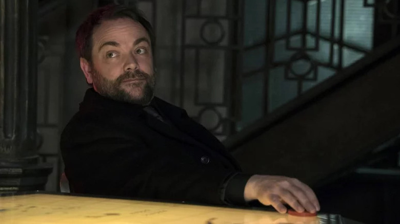 Mark Sheppard's Crowley sitting at a table on Supernatural