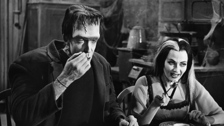 Fred Gwynne as Herman Munster and Yvonne De Carlo as Lily Munster eating food in The Munsters