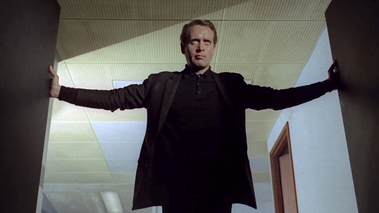Number Six (Patrick McGoohan) sternly looks ahead as he opens a door in The Prisoner (1967)